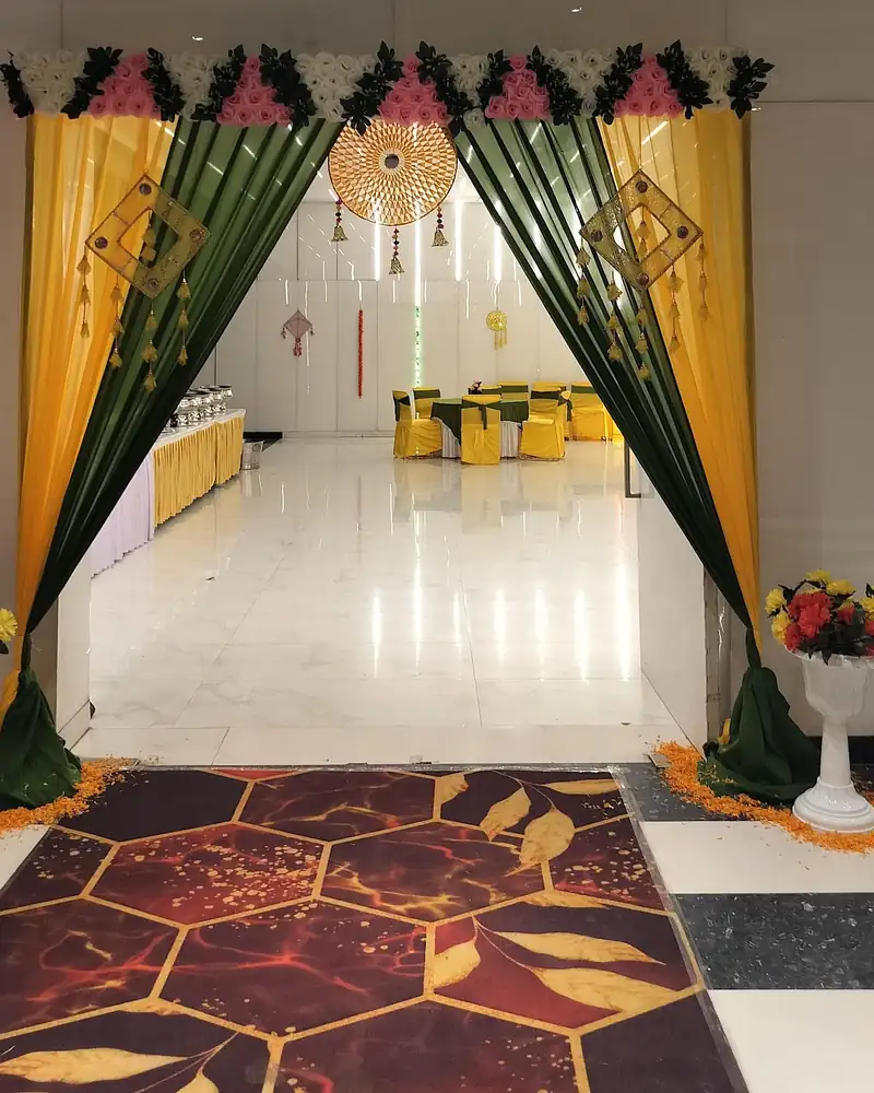 Green and yellow drapes framing a hall entrance with hanging ornaments and flower urns.