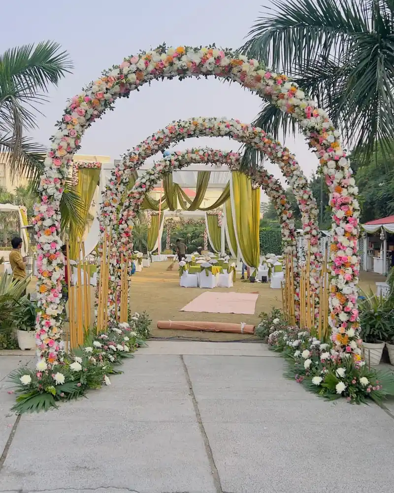 A line of flower arches over a garden path leading to a decorated seating area.